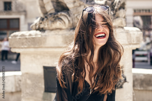 Fotografie happy stylish woman with gorgeous smile and hair, having fun in sunlight in city street