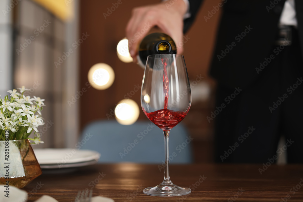 Man pouring wine into glass on table