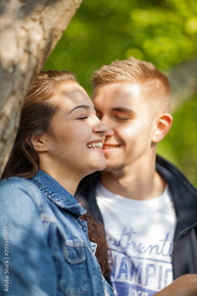 Young couple having fun, talking, flirting in a sunny park in springtime, beautiful, romantic mood