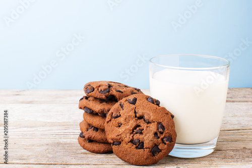 chocolate chip cookies and a glass of milk on a light table, on a blue background photo