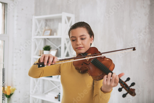 Melody of soul. Cheerful musician looking downwards while playing the violin
