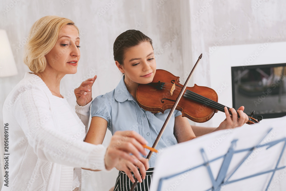 Repeat again. Attentive girl using her violin while remembering solfeggio Repeat again. Attentive girl using her violin while remembering solfeggio
