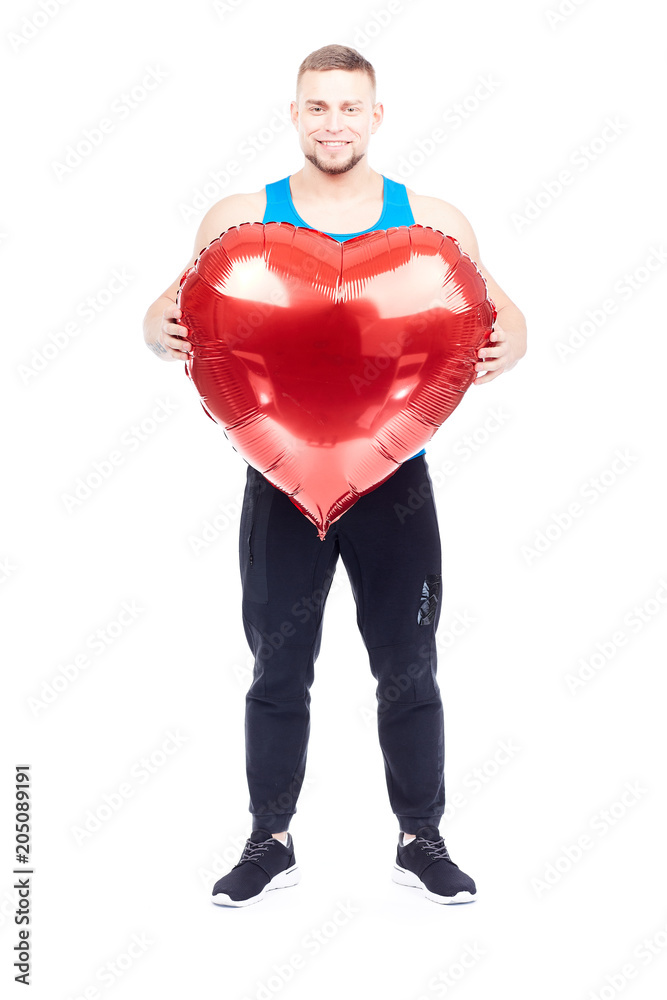 Portrait of athlete holding big red heart-shaped balloon isolated on white Portrait of athlete holding big red heart-shaped balloon isolated on white