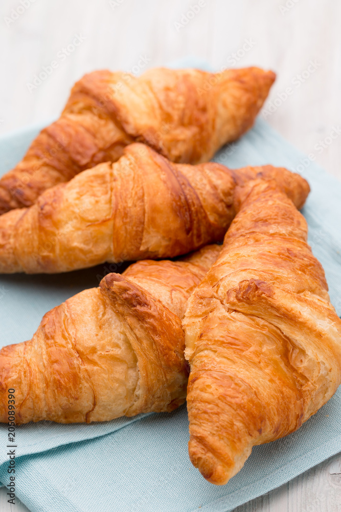 Tasty buttery croissants on old wooden table.