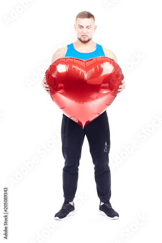 Portrait of athlete holding big red heart-shaped balloon isolated on white