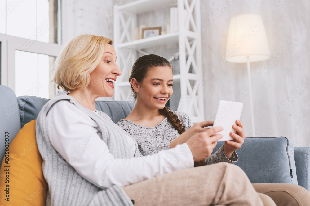 Video call. Charming girl expressing positivity while staring at screen of modern gadget Video call. Charming girl expressing positivity while staring at screen of modern gadget