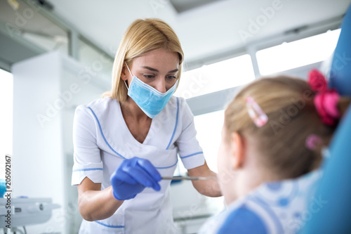 Dentist with sterile mask and dental instruments held exam teeth of patient