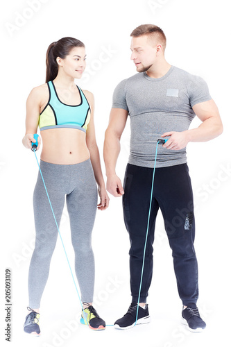 Full-length portrait of fit couple in sports clothes posing on white background
