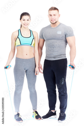 Full-length portrait of fit couple in sports clothes posing on white background