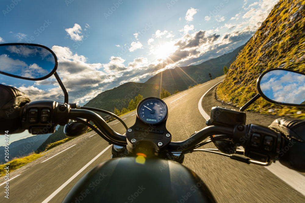 Fototapeta premium Motocyklista jazda w alpejskiej autostradzie, widok na kierownicę, Austria, Europa.