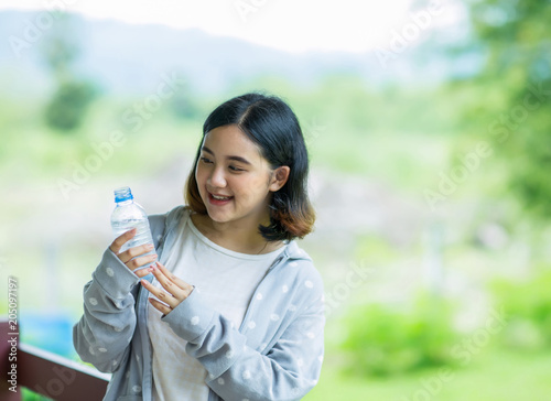 asian girl holding a bottle of cold water