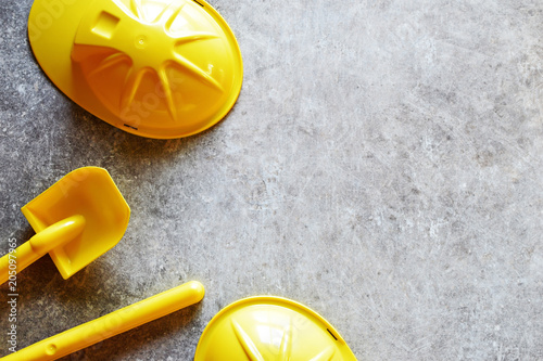 Wallpaper Mural Bright yellow plastic children toy shovels on grey grunge table background with copy space for text. Torontodigital.ca