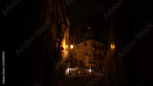 Alley on hill at night with carlights appearing, Alfama district in Lisbon.