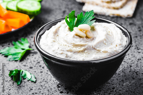 White bean dip on dark concrete background. Selective focus, space for text. 