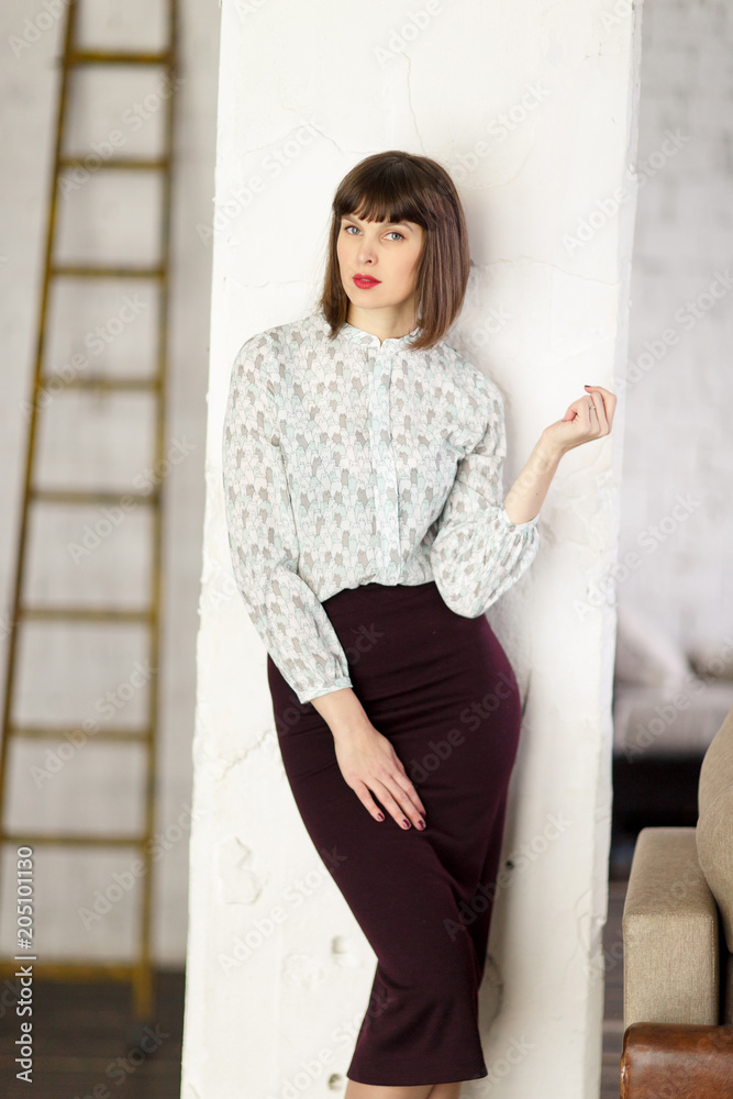 Photo of young brunette in blouse near wall