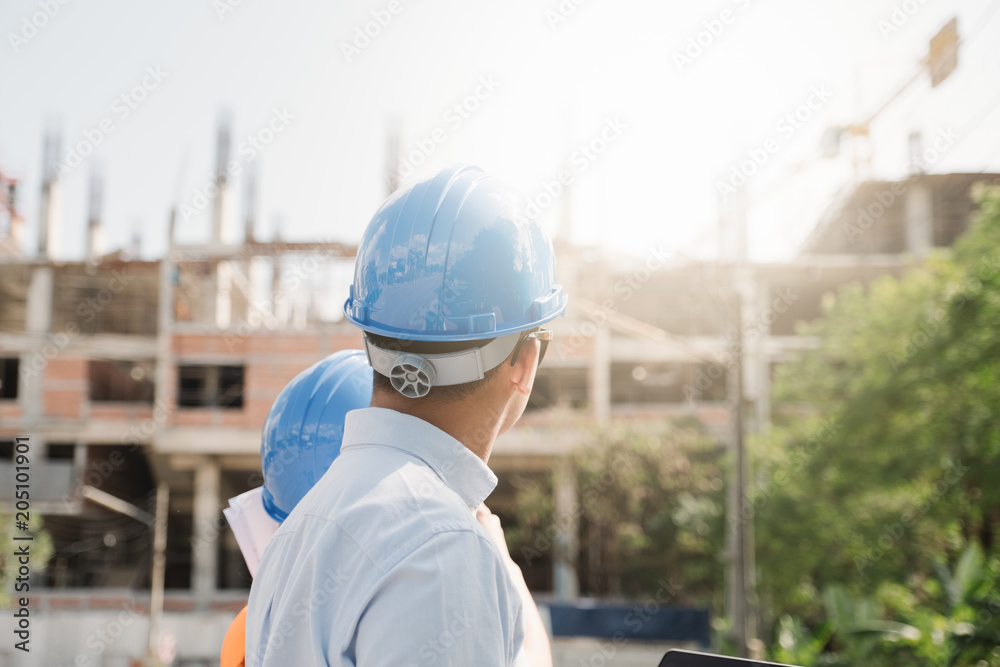 Architects And Engineer at a construction site looking at blueprints and pointing. Architects And Engineer at a construction site looking at blueprints and pointing.