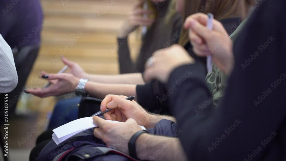 Close-up of Hands holding pens and making notes at the conference. Close-up of Hands holding pens and making notes at the conference.