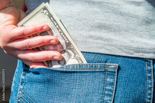 Woman hand putting money in jeans pocket