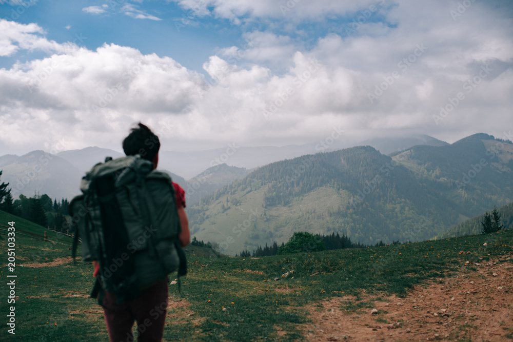 Incredible mountains. Portrait of a guy with a backpack from behind. Focus on the mountains