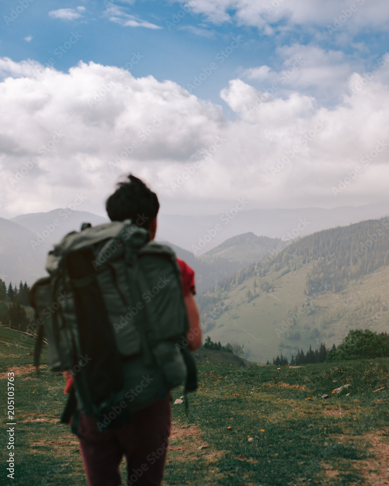 Incredible mountains. Portrait of a guy with a backpack from behind. Focus on the mountains