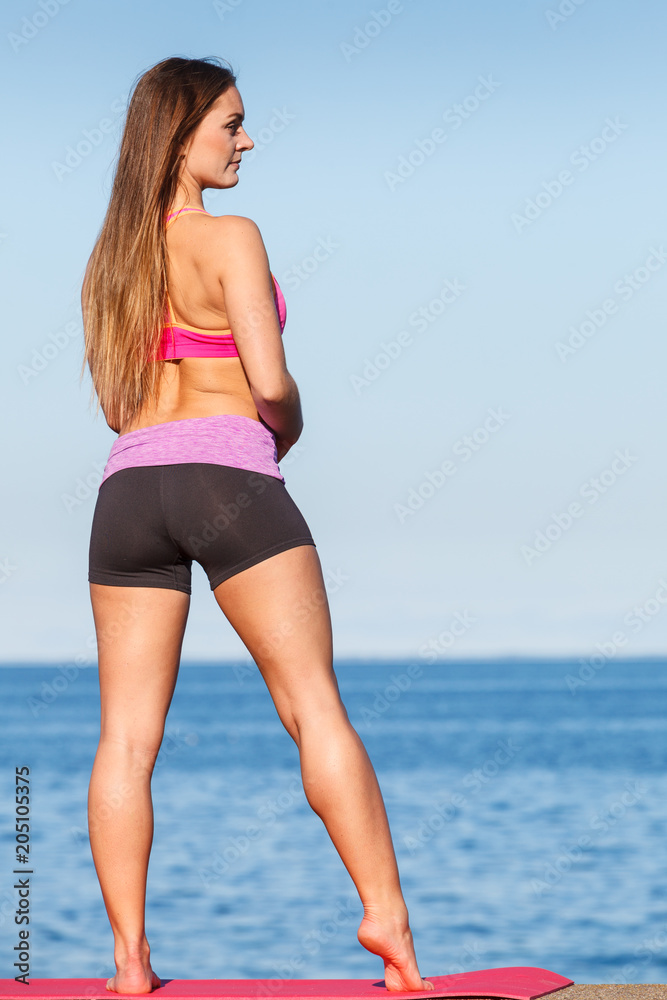 Woman in sportswear standing on dyke by sea Woman in sportswear standing on dyke by sea