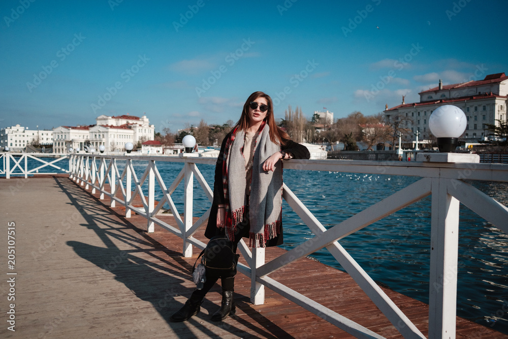Cheerful female walking on city street enjoying free time on spring weekends, happy woman in sunglasses evokes sea fresh air