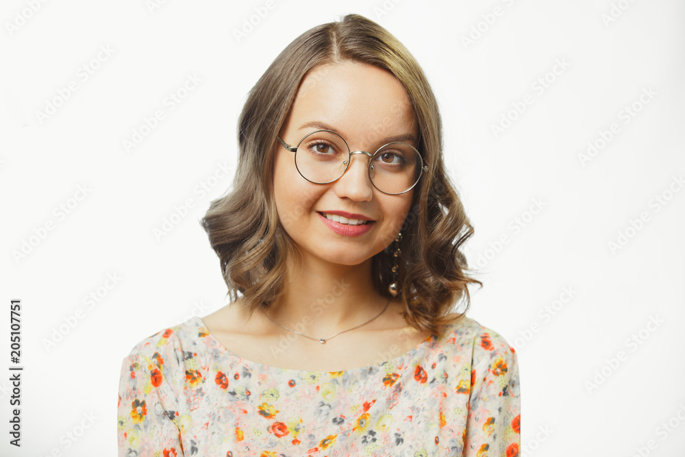 portrait of young woman wearing floral blouse, round eyeglasses for vision, has light brown hair up to shoulders, with sincere look and charming smile. portrait of young woman wearing floral blouse, round eyeglasses for vision, has light brown hair up to shoulders, with sincere look and charming smile.