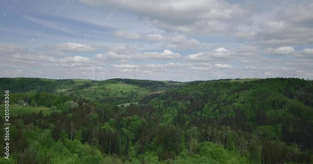 Windmills standing on forested hills aerial of renewable energy production Windmills standing on forested hills aerial of renewable energy production