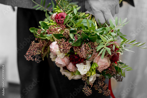 man's hands with a bouquet of flowersthe groom holds a wedding bouquet in handsdelicate wedding bouqueta man in a suit with a bouquet of flowers photo