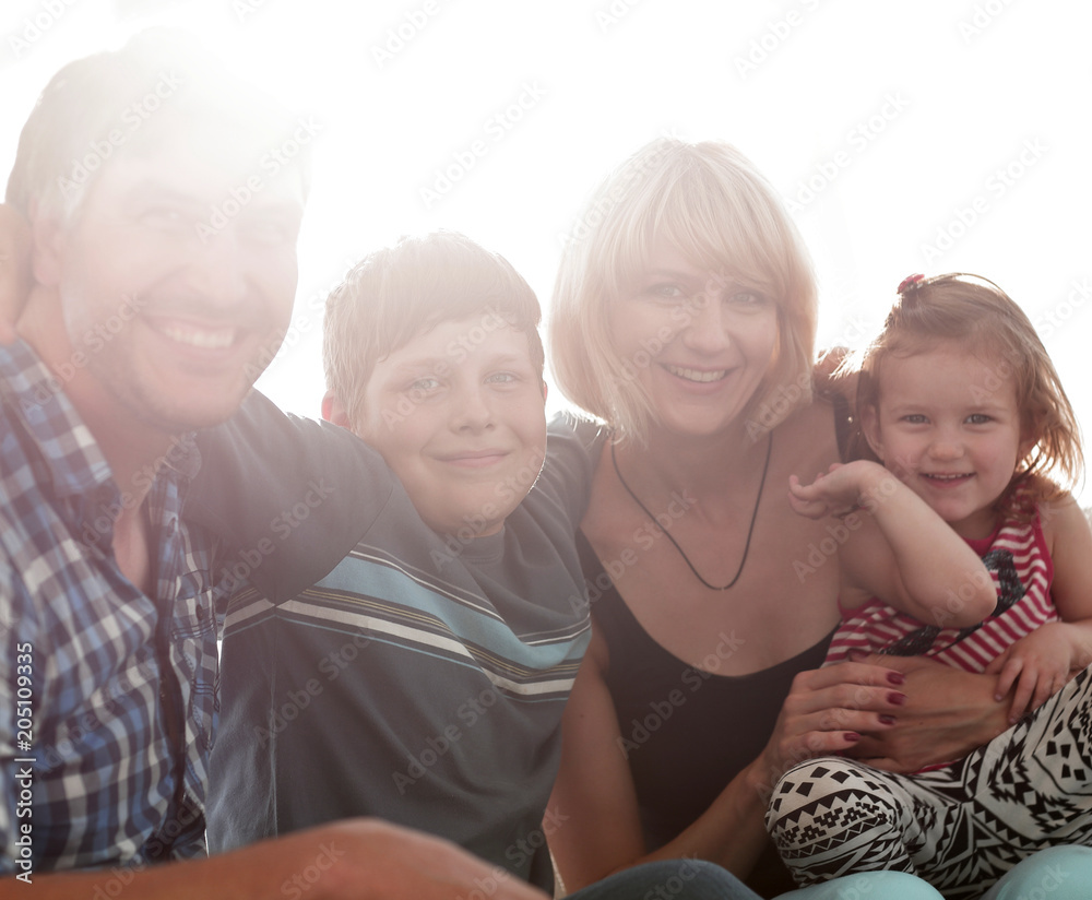 family with two children sitting together and looking at camera family with two children sitting together and looking at camera