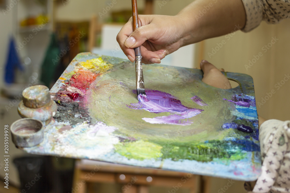 Fototapeta premium The artist's hands are mixing paints with a palette