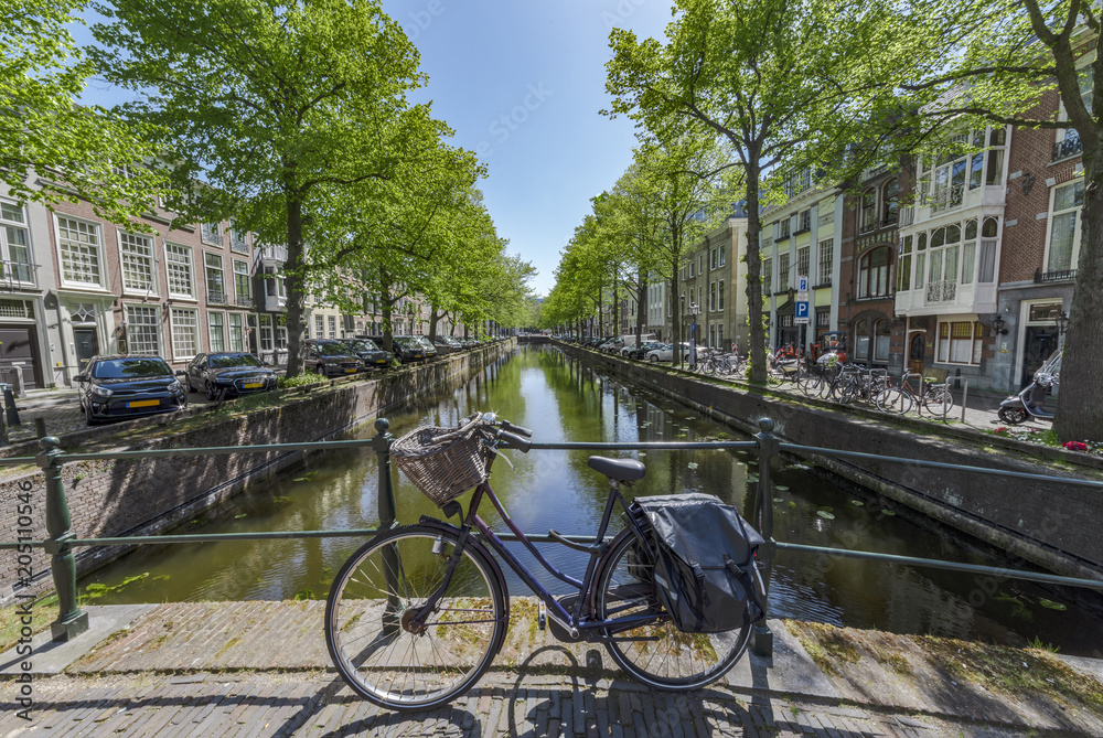 Iconic scene of Amsterdam with the bicycle parked on a bridge over a calm water canal, Netherlands