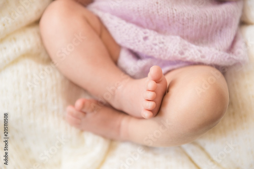 Feet of a newborn baby close-up on white blanket
