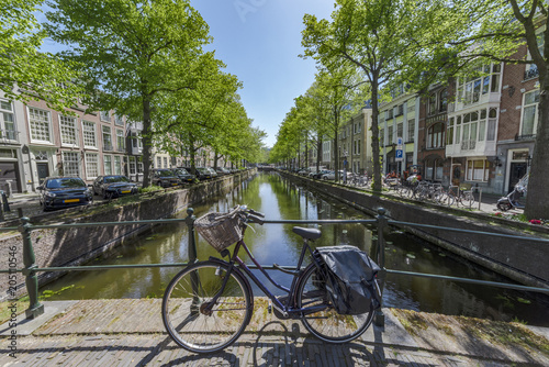 Iconic scene of Amsterdam with the bicycle parked on a bridge over a calm water canal, Netherlands