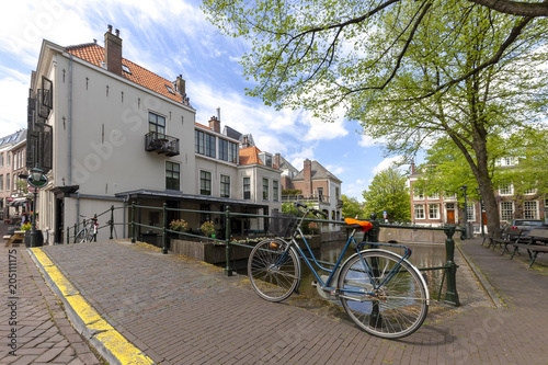 Typical Dutch cityscape with a little brick bridge over a calm canal where a heavy stainless Dutch bicycle is parked at the lunch time, The Hague, Netherlands