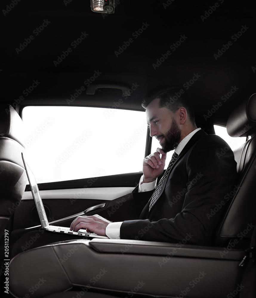 confident businessman sitting on the backseat of a prestigious car