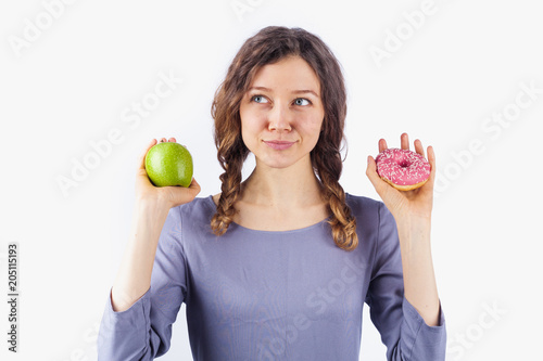 Woman choosing between an apple and a donut.