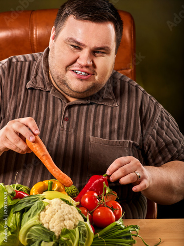 Diet fat man eating healthy food with vegetables cauliflower and sweet pepper with radish, tomatoes for overweight male. Male trying to lose weight first time. Hungry person ready to eat everything