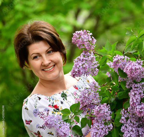 Smiling woman in alilac garden