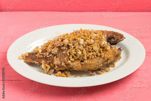 asia-asian food. thai food. fried nile tilapia river fish with garlic. on dish ceramic. on pink wood background