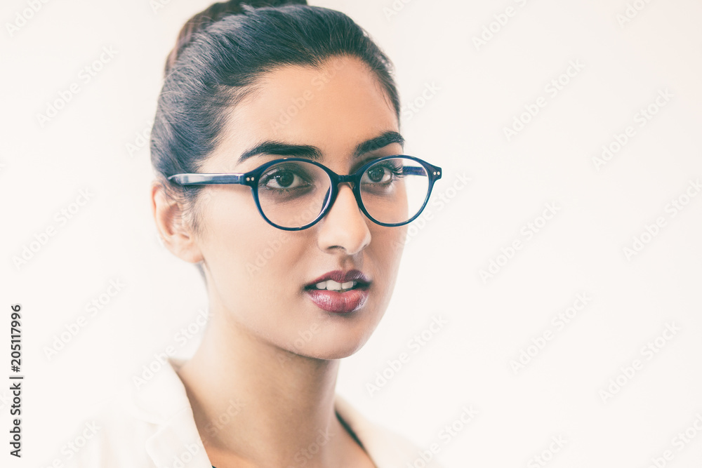 Closeup portrait of serious young pretty Indian woman looking aside and  wearing glasses with her hair tied back in bun. Isolated view on white  background. Stock Photo | Adobe Stock