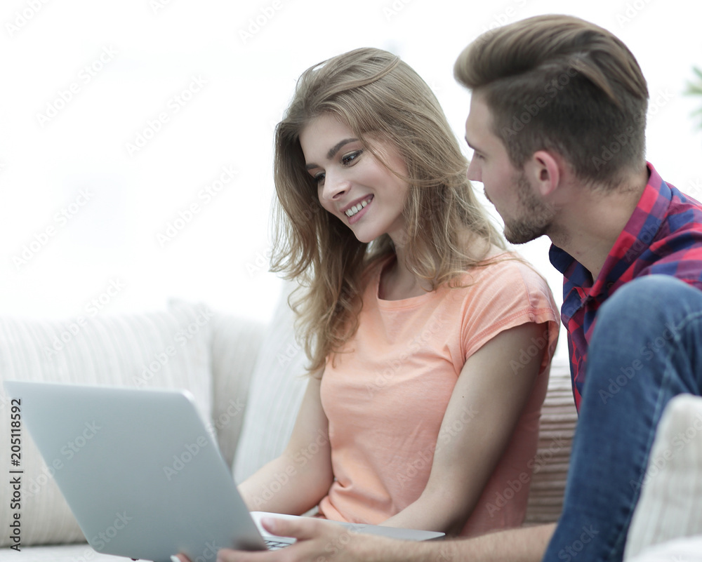 young couple sitting on sofa and looking at pictures on the laptop. young couple sitting on sofa and looking at pictures on the laptop.