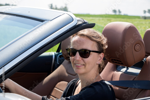 Happy beautiful Woman Driving in Luxury Convertible Sports Car - View with car interior © Riko Best