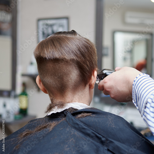 Hairdresser making a haircut to a boy with clipper.