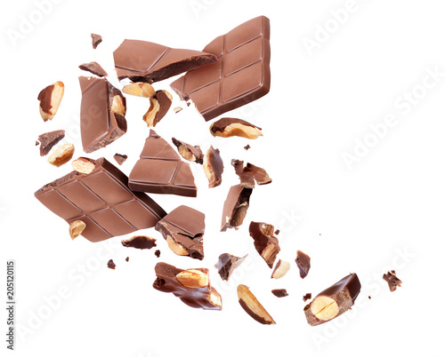 Chocolate bar with nuts broken into pieces in the air on a white background