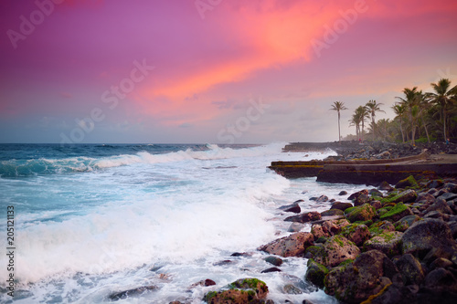 Beautiful pink tinted waves breaking on a rocky beach at sunrise on east coast of Big Island of Hawaii