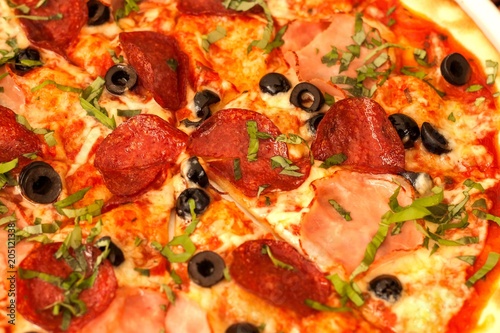 Homemade salami pizza with ham and olives. Close-up view of fresh pizza.