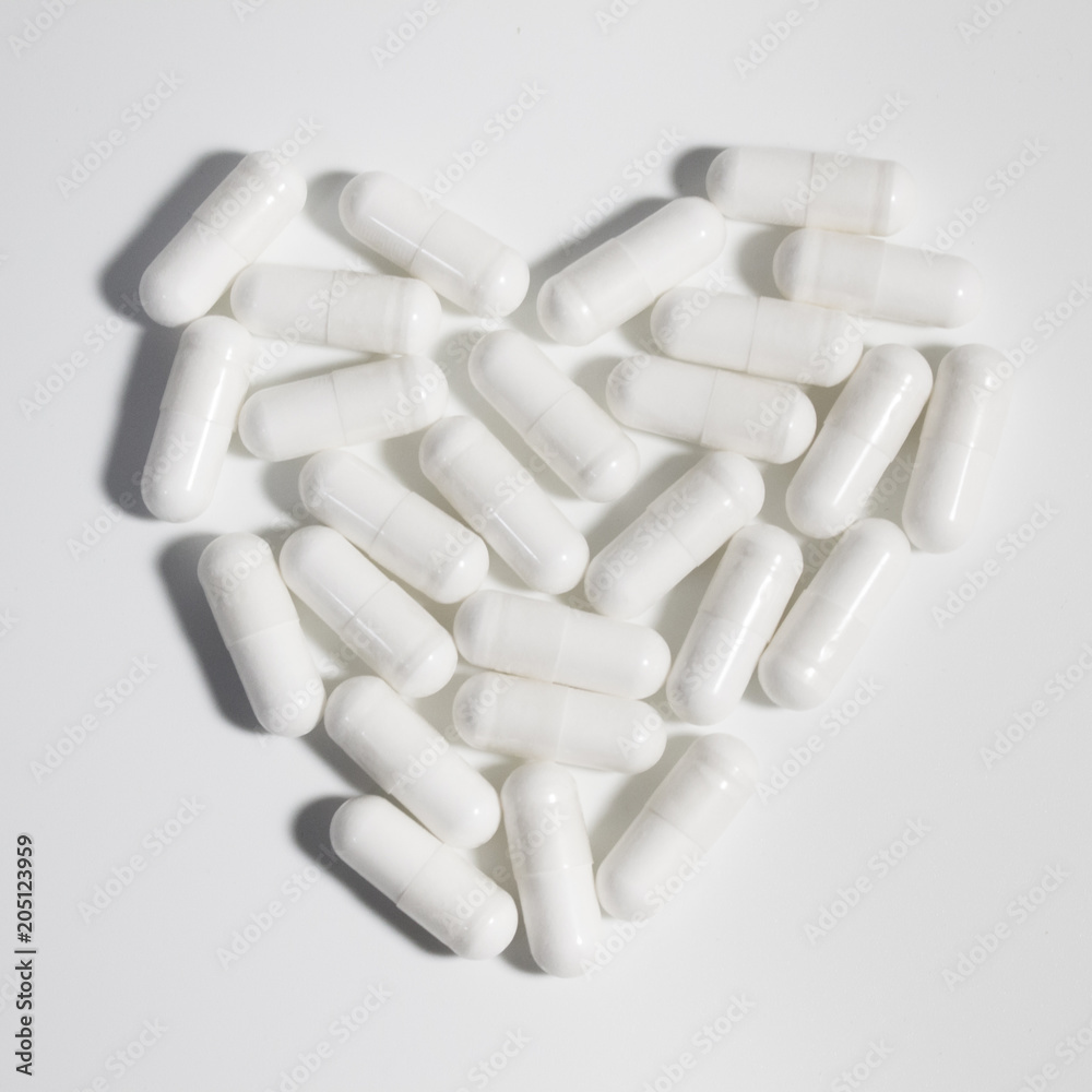 Heart made of white capsules medications on white background. Heart made of white capsules medications on white background.