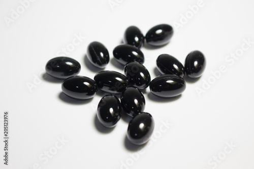 Black supplement capsule on white background
