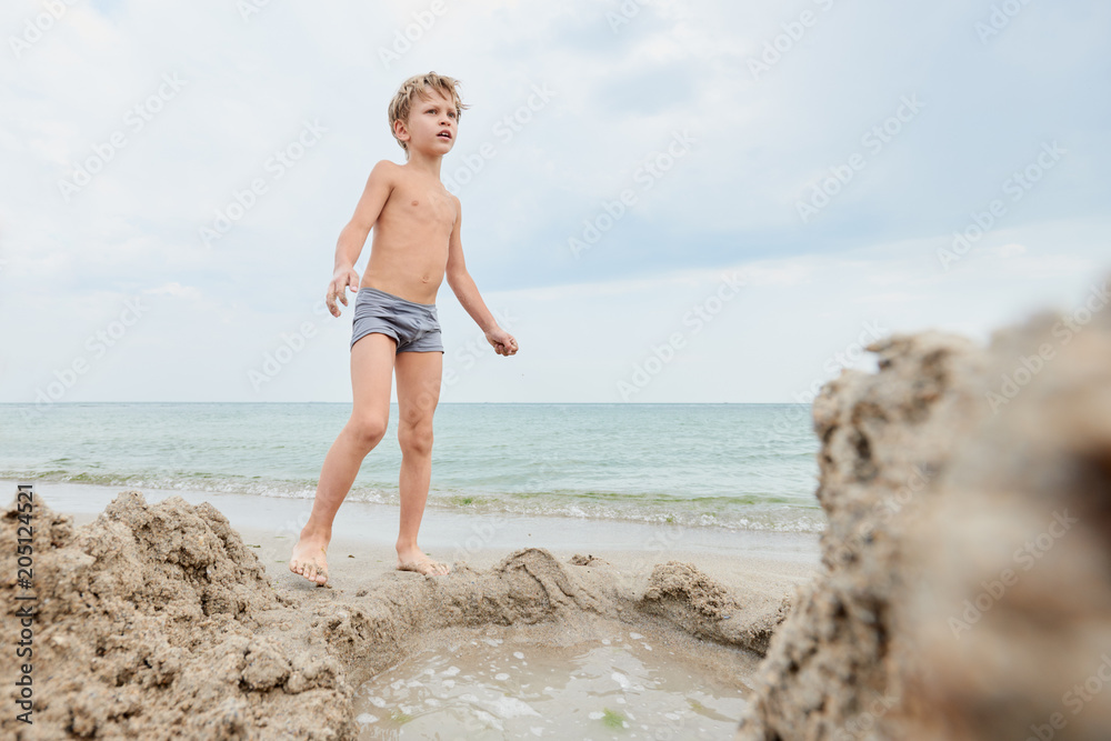 Portrait of young blond boy having fun on the seashore